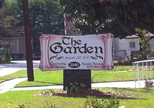 Welcoming sign for The Garden, a sober living home in Atlanta, featuring lush green landscaping.