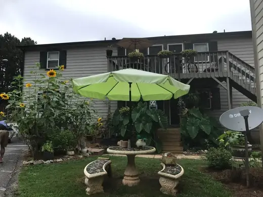 Green patio umbrella over a stone table at Valor House, a sober living home in Atlanta.